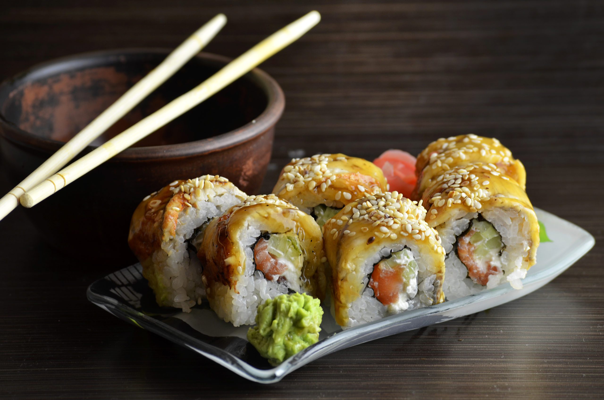a plate of sushi rolls with chopsticks and wasabi