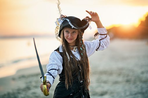 Child dressed as a pirate on the beach with sword