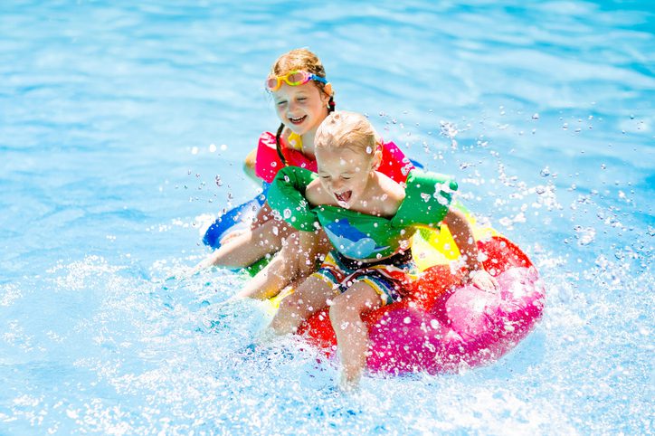 Kids on inflatable float in swimming pool.