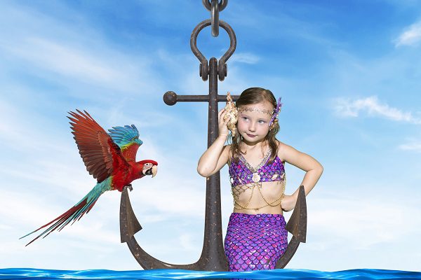 little girl dressed as mermaid sitting on anchor