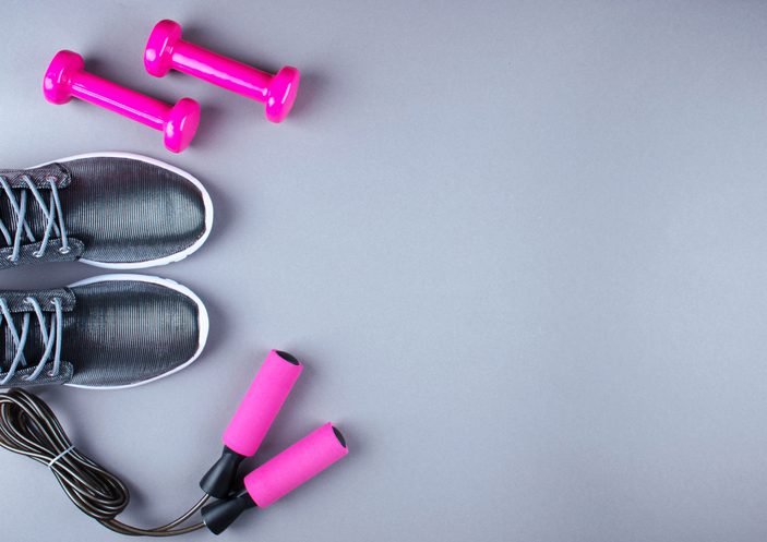 Flat lay shot of sneakers, jumpung rope and dumbbells.